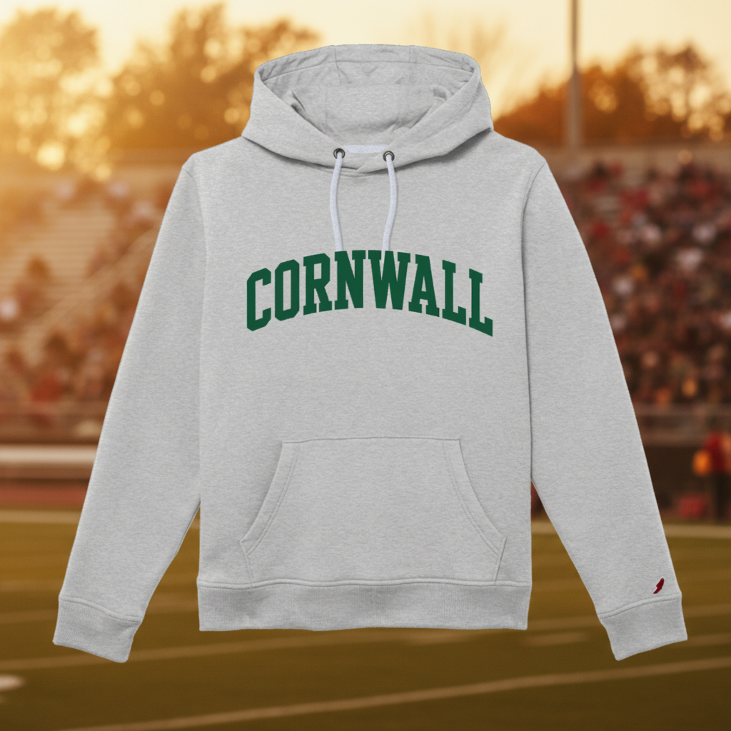 A light heather gray pullover hoodie with 'CORNWALL' printed in dark green varsity-style block letters across the chest. The hoodie features white drawstrings, a front kangaroo pocket, and a small red embroidered bird logo on the left sleeve cuff, shown against a plain white background.